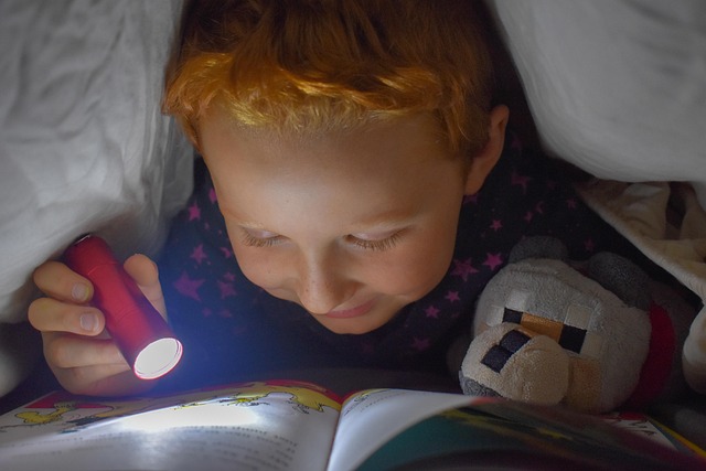 boy lying down reading book with flashlight in calm down corner
